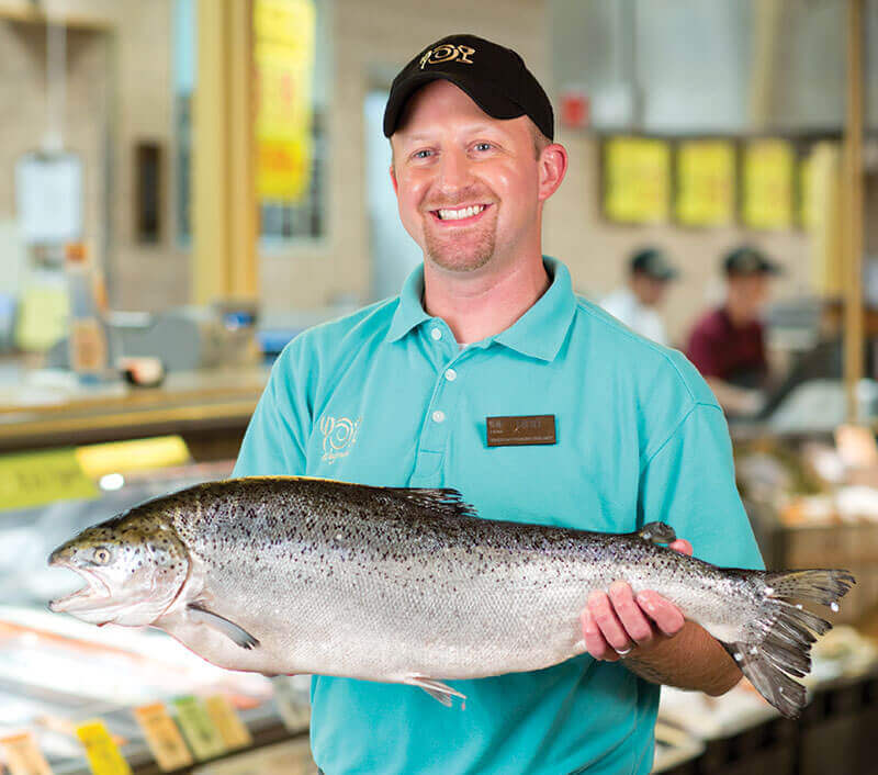 Wegmans seafood employee holding a fish