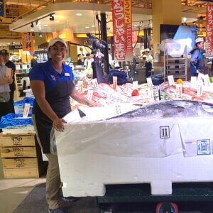 Wegmans employee smiling next too cooler with 200 pound tuna in it