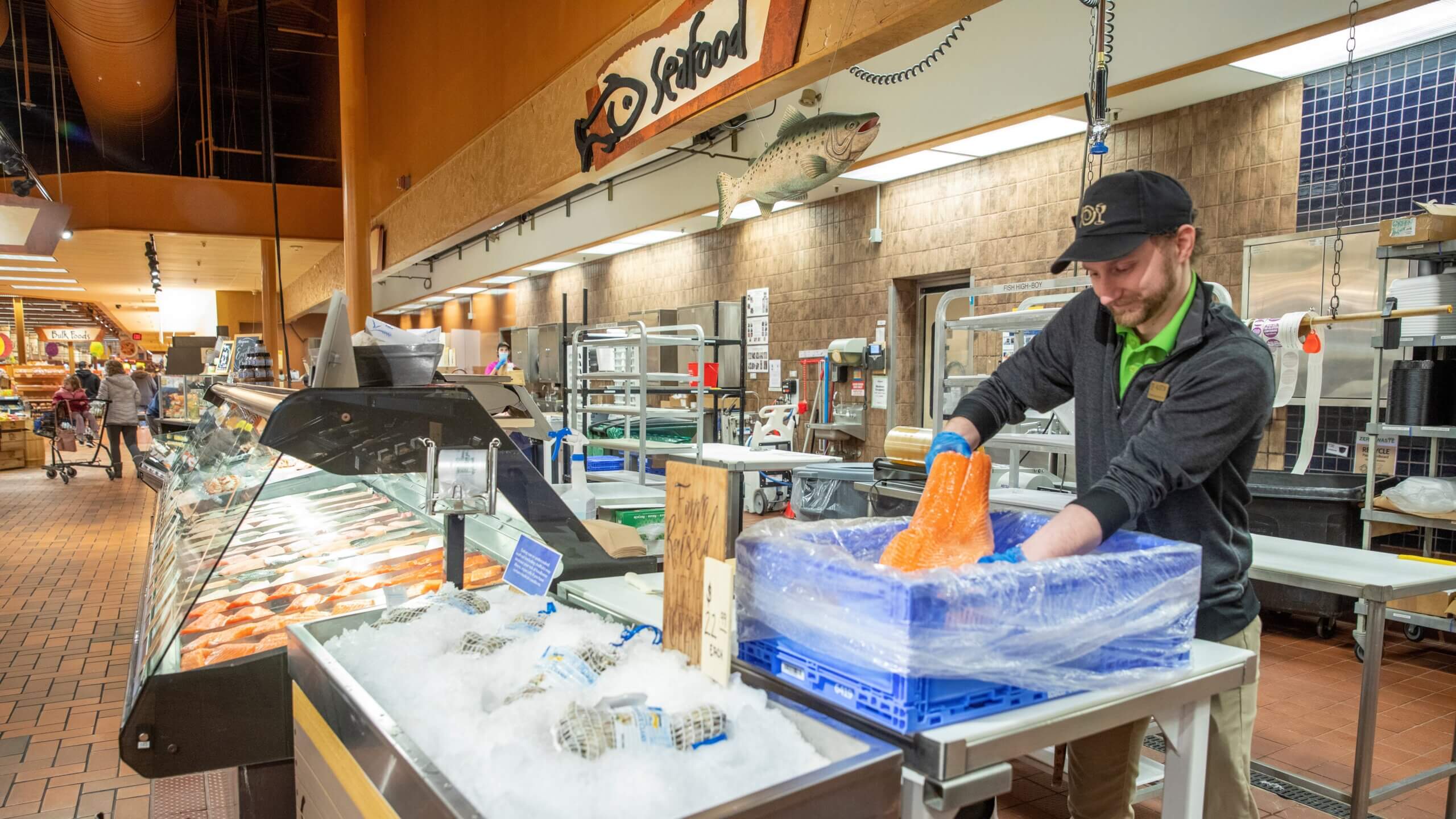 Wegmans employee unloads salmon from reusable plastic container.